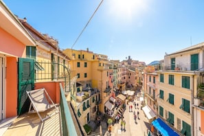 A narrow street with buildings on either side, balconies, and a clear sky.