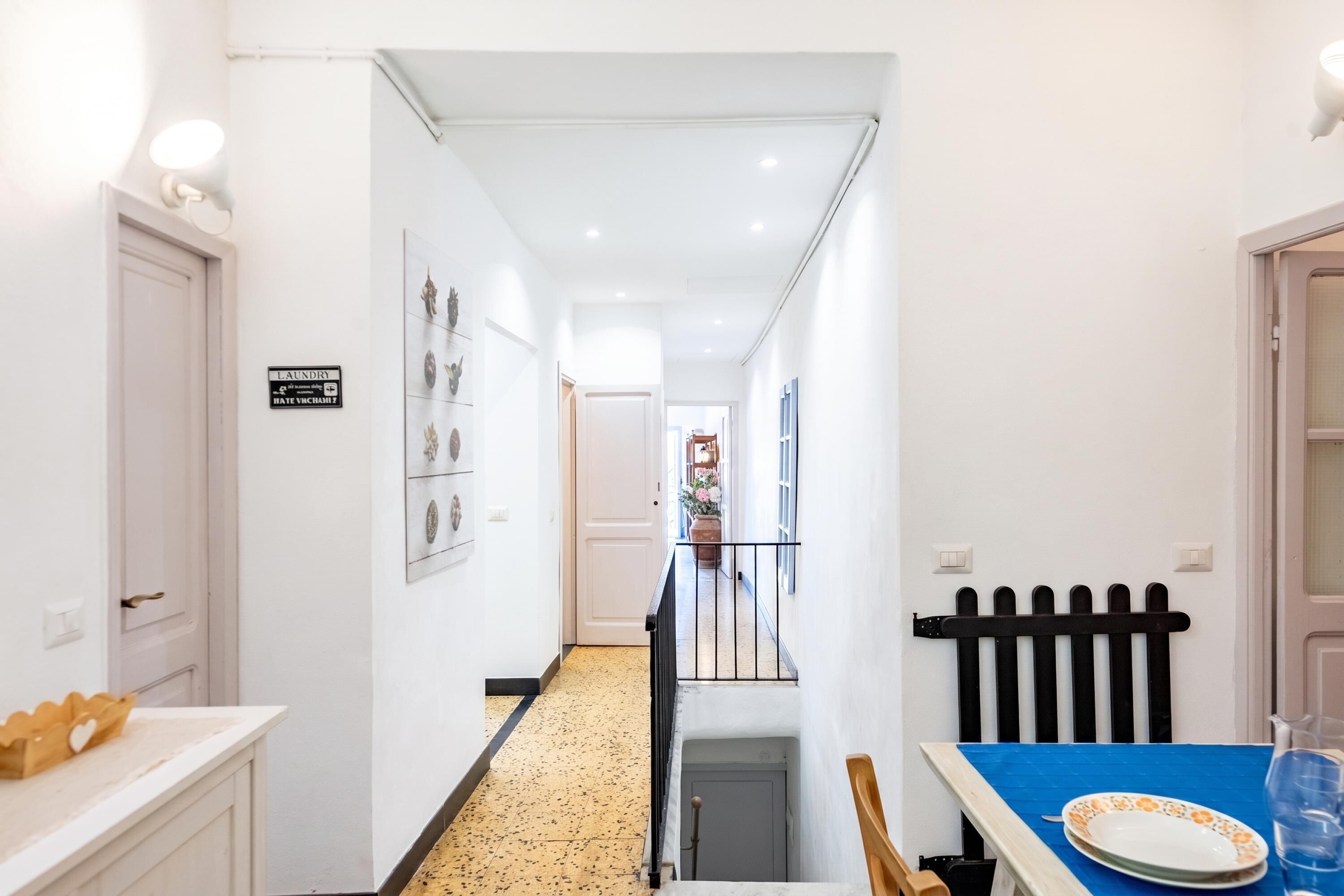 A narrow hallway with a dining area at the end, featuring a table with plates and a pitcher.