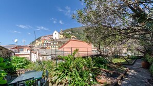A courtyard with a table and chairs, surrounded by greenery and a view of a hillside with buildings. - Charming Apartment With Balcony In Vernazza (Vernazza)