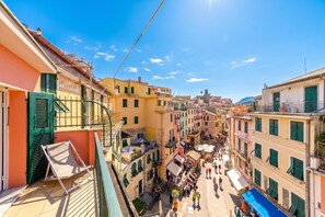 A narrow street with buildings on either side, a clear sky, and a few people walking. - Charming Apartment With Balcony In Vernazza (Vernazza)