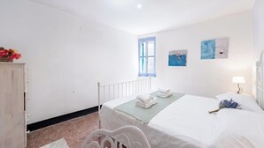 A bedroom with a bed, a nightstand, a lamp, and a window. - Charming Apartment With Balcony In Vernazza (Vernazza)