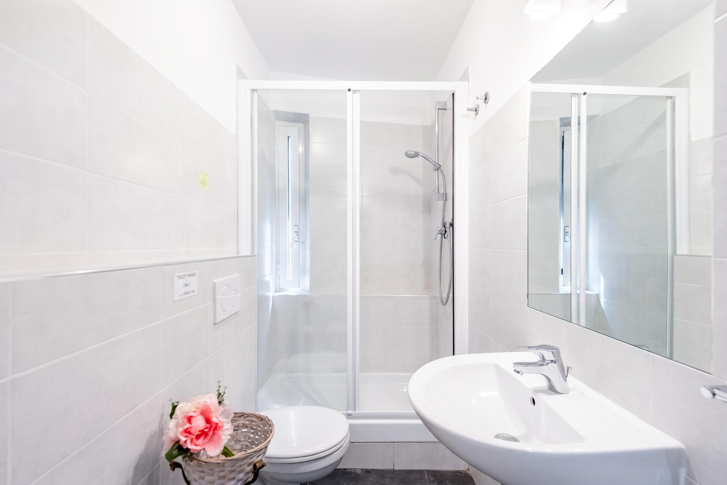 Ein modernes Badezimmer mit einer gläsernen Duschkabine, einem weißen Waschbecken und einer Toilette.