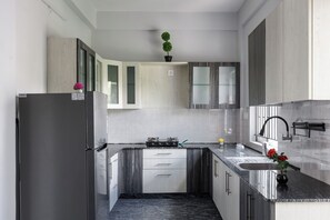 A modern kitchen with a built-in stove, a sink, and a countertop. - Galaxy 4th Block by Red Olive (Bengaluru)