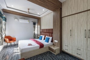 A modern bedroom with a bed, a chair, a wardrobe, and an air conditioning unit. - Galaxy 4th Block by Red Olive (Bengaluru)
