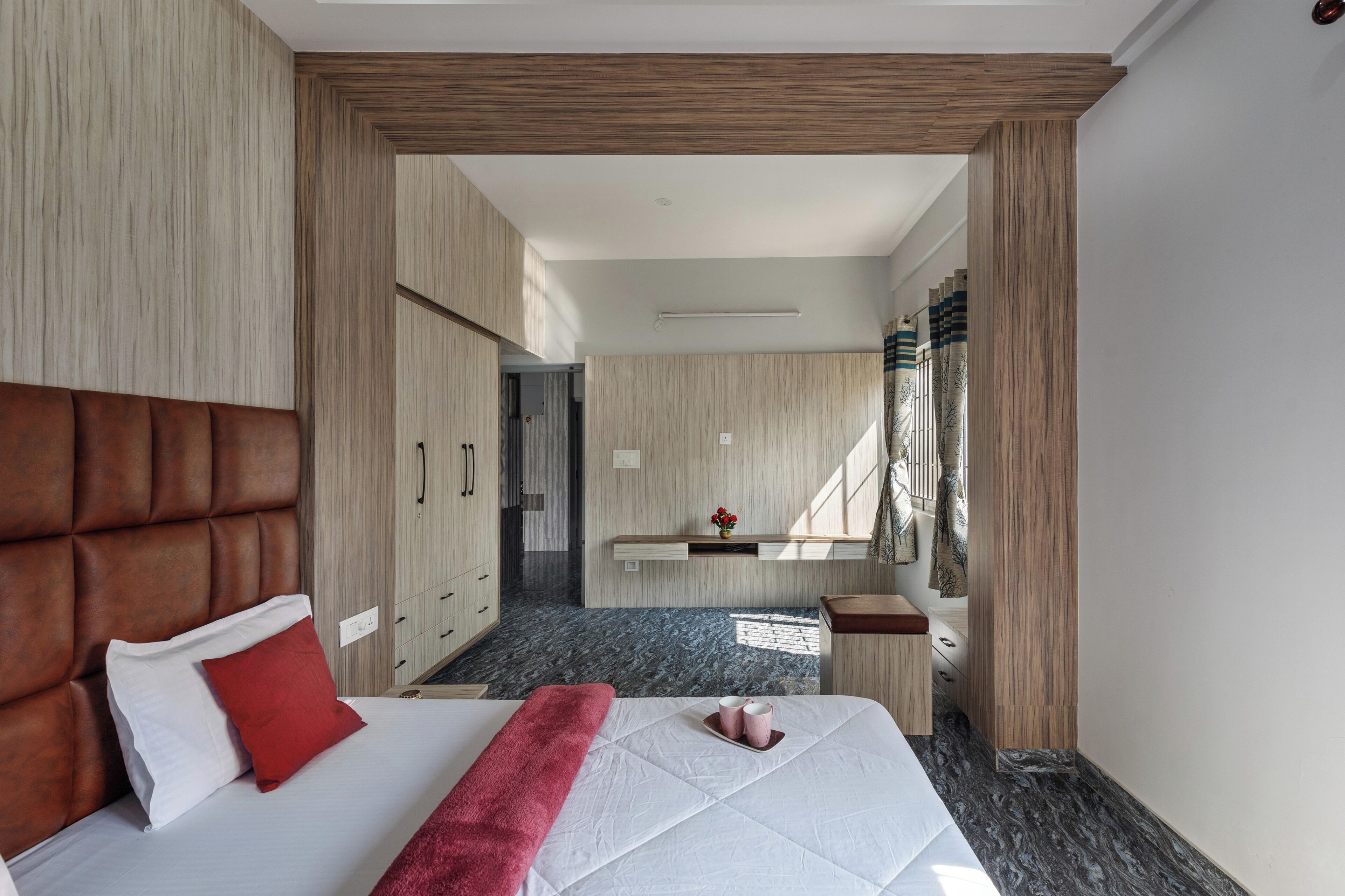 A modern hotel room with a large bed, wooden headboard, and a small bathroom area.