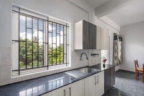A modern kitchen with a large window, a sink, and a chair. - Galaxy 4th Block by Red Olive (Bengaluru)