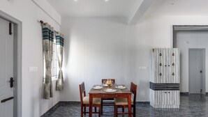 A dining area with a marble floor, a wooden dining table set for four, and a cabinet with a patterned design. - Galaxy 4th Block by Red Olive (Bengaluru)