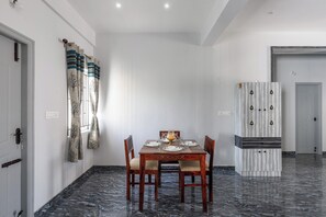 Een eetruimte met een marmeren vloer, een houten eettafel voor vier personen en een kast met een decoratief patroon.