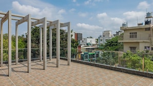 A rooftop terrace with a metal framework and tiled flooring, overlooking a residential area with buildings and greenery. - Galaxy 4th Block by Red Olive (Bengaluru)