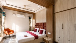 A modern hotel room with a bed, a wooden wardrobe, a small bedside table, and a chair. - Galaxy 4th Block by Red Olive (Bengaluru)