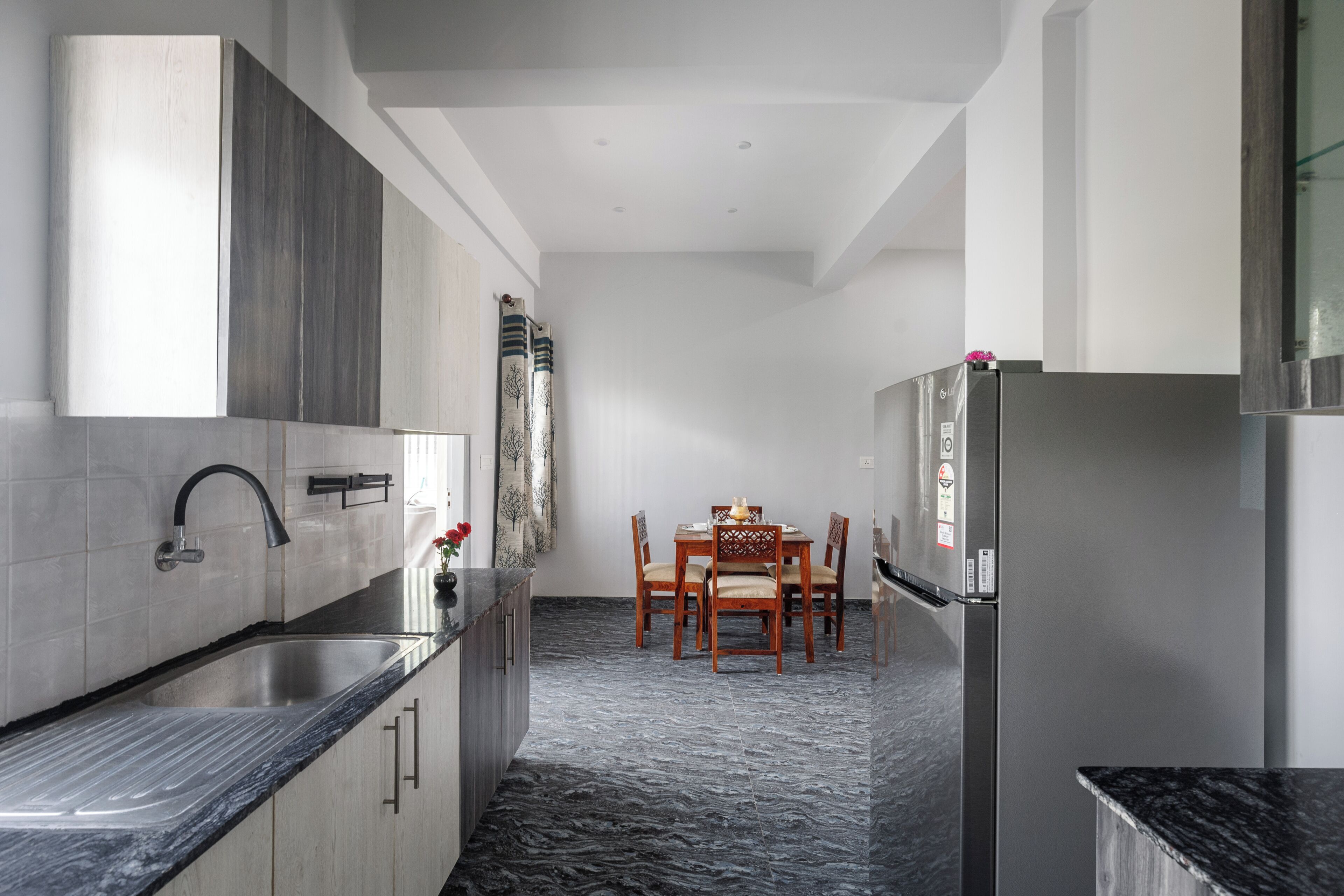 Eine moderne Küche mit integriertem Spülbecken, einem Essbereich mit Tisch und Stühlen sowie einem Kühlschrank.