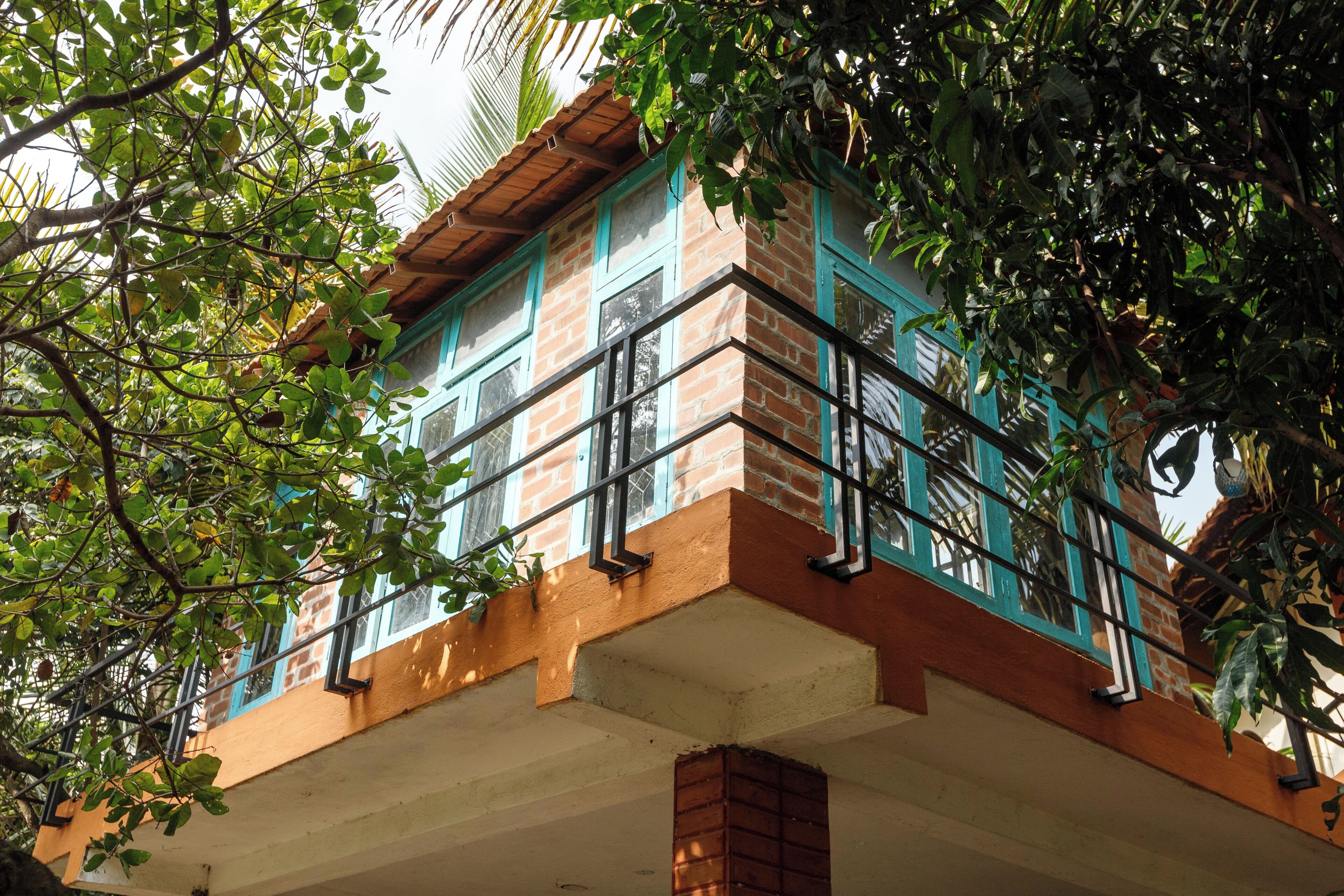 Un edificio de varios pisos con fachada de ladrillo, marcos de ventana azules y un balcón con barandillas negras.
