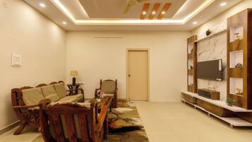 A living room with a sofa, armchair, coffee table, TV stand, and a ceiling fan.