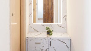 Un couloir avec un mur de marbre, une porte en bois et un miroir doté d’un cadre en bois.