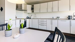 Een moderne keuken met witte kasten, een witte tafel en twee potorkideeën.