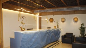Un mostrador de recepción con un diseño azul ondulado, techo de madera y relojes de pared que marcan diferentes husos horarios.