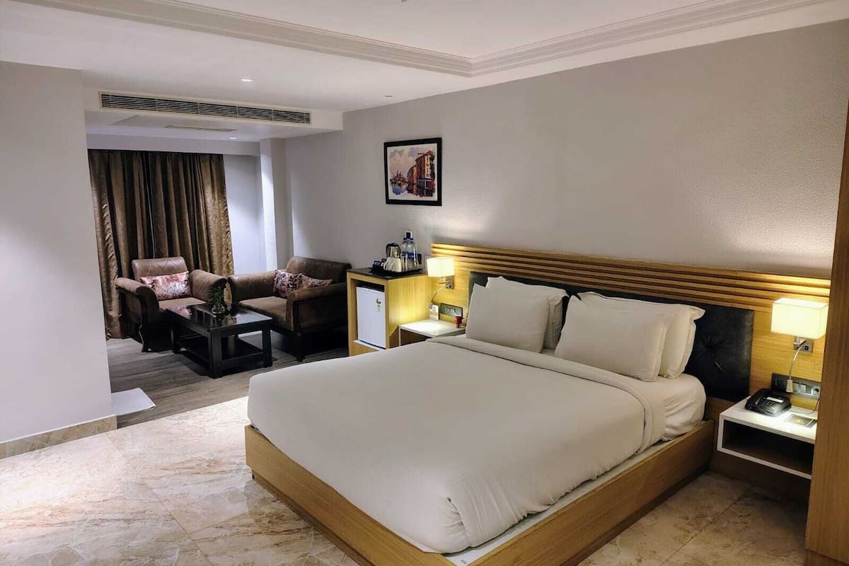 A hotel room with a large bed, a desk, a chair, and a small table.