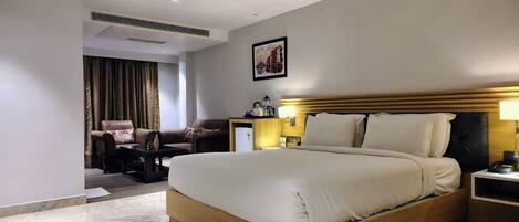 A hotel room with a large bed, a desk, a chair, and a small table.