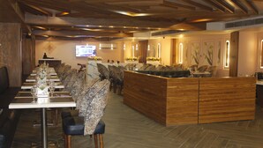 Un restaurante con una mesa larga comunal, cabinas individuales y un mostrador de recepción de madera.
