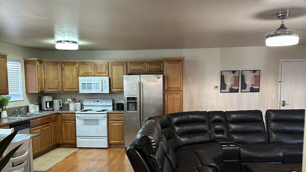 A modern kitchen with wooden cabinets, a stainless steel refrigerator, and a white stove.