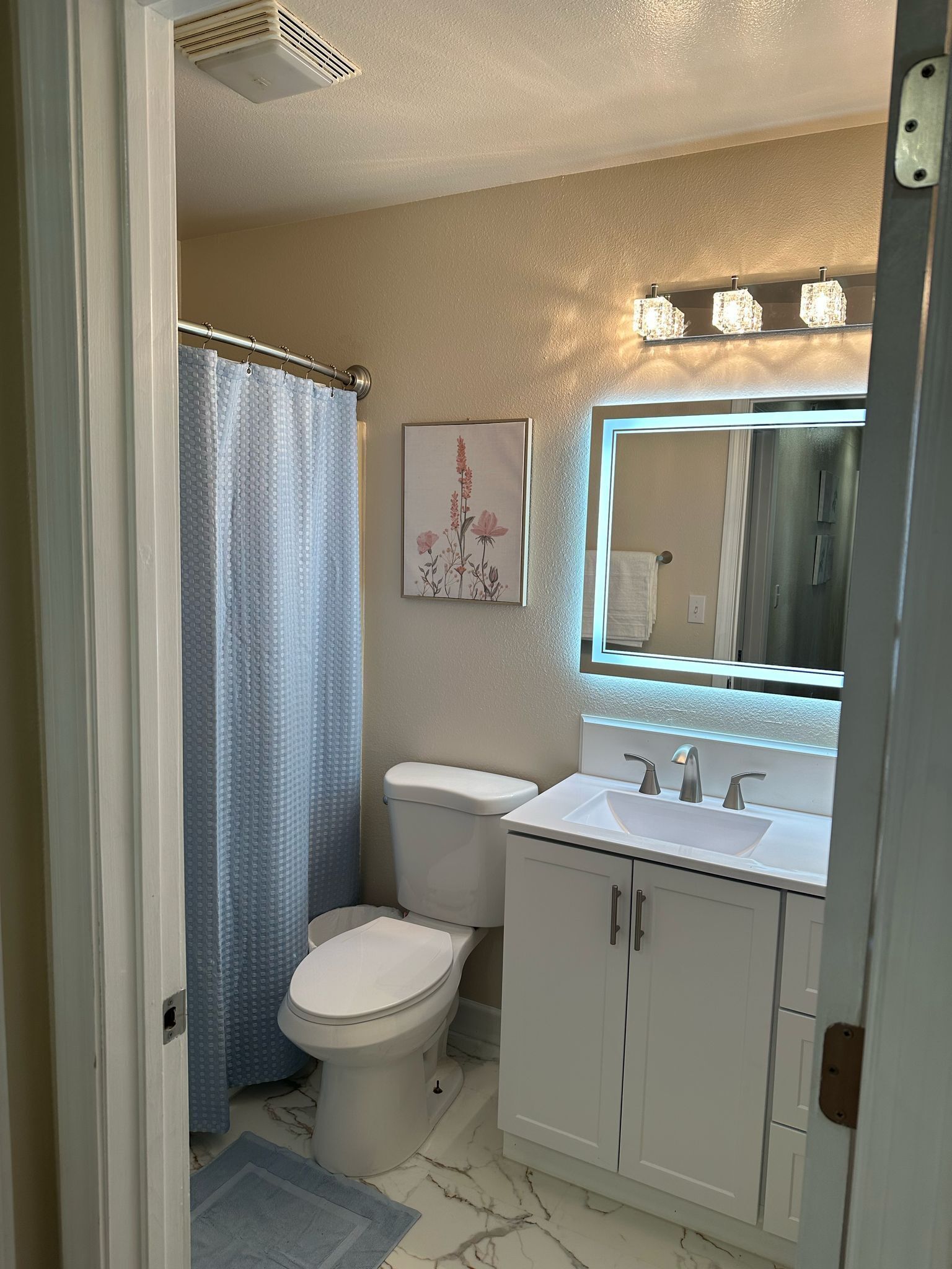 A bathroom with a toilet, sink, and shower curtain.