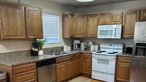 A kitchen with wooden cabinets, a stainless steel dishwasher, a white stove, and a microwave.