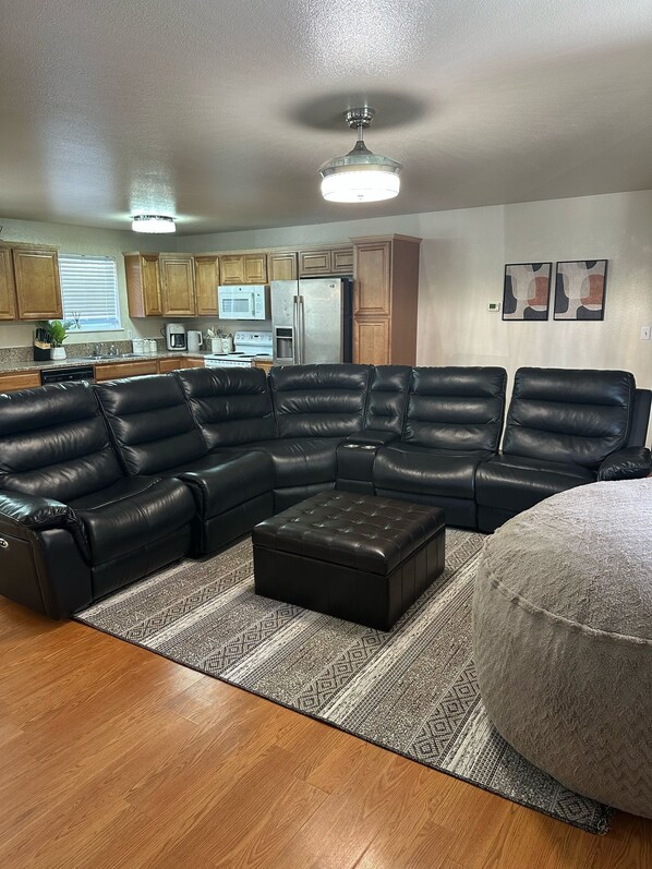 A modern living room with a sectional sofa, a coffee table, and a round ottoman.