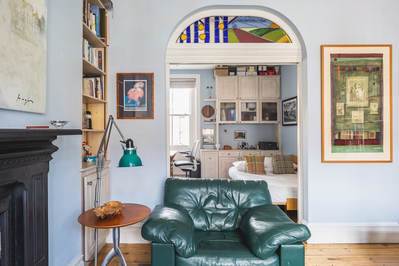 A cozy living room with a green leather armchair, a small wooden table, and a bookshelf filled with books.