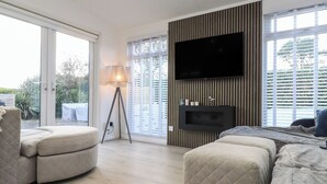 Un salon moderne avec une grande télévision, un lampadaire et un canapé.