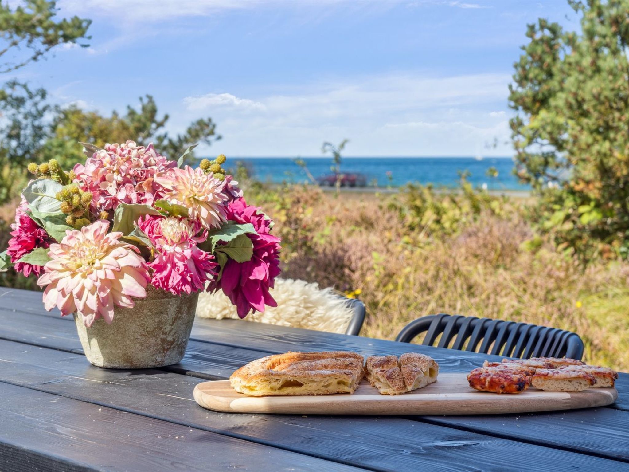 Una mesa de picnic con un arreglo floral y porciones de pizza.