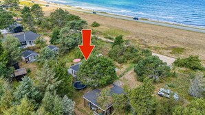 An aerial view of a coastal property with a beach, houses, and a road.