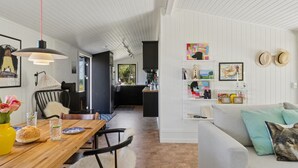 A modern interior with a wooden dining table, chairs, a sofa, and a kitchen area.