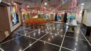 A spacious hall with a polished black floor, rows of chairs, and a stage area. - Hotel Eminent (Agra)