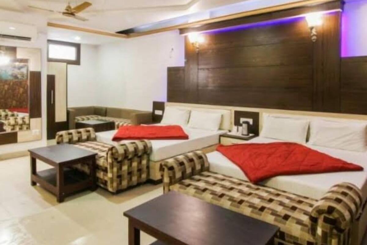 A hotel room with a sofa set, a bed, a small table, and a ceiling fan.