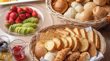 Uma mesa com cestos de pão, fatias de pão e frutas.