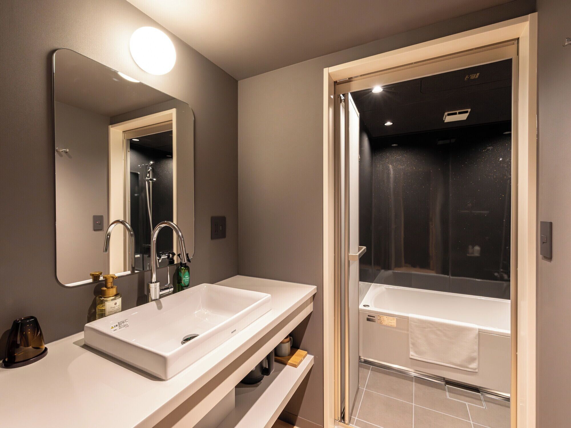 A modern bathroom with two sinks, a large mirror, and a glass-enclosed shower.