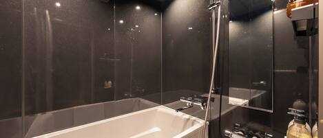 Ein modernes Badezimmer mit einer großen Badewanne, einer Dusche und einem Spiegel.