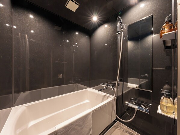 A modern bathroom with a large bathtub, a shower, and a mirror.