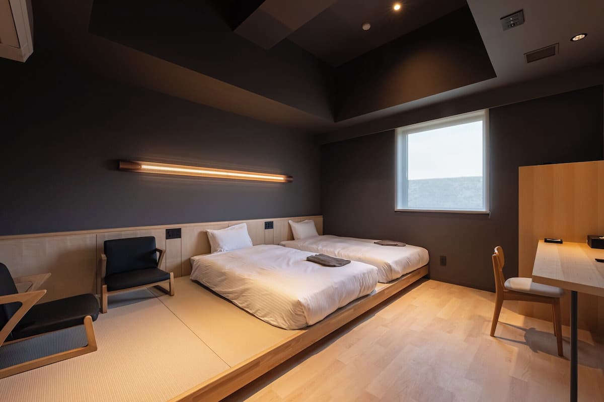 A modern hotel room with a large bed, a desk, and a chair.