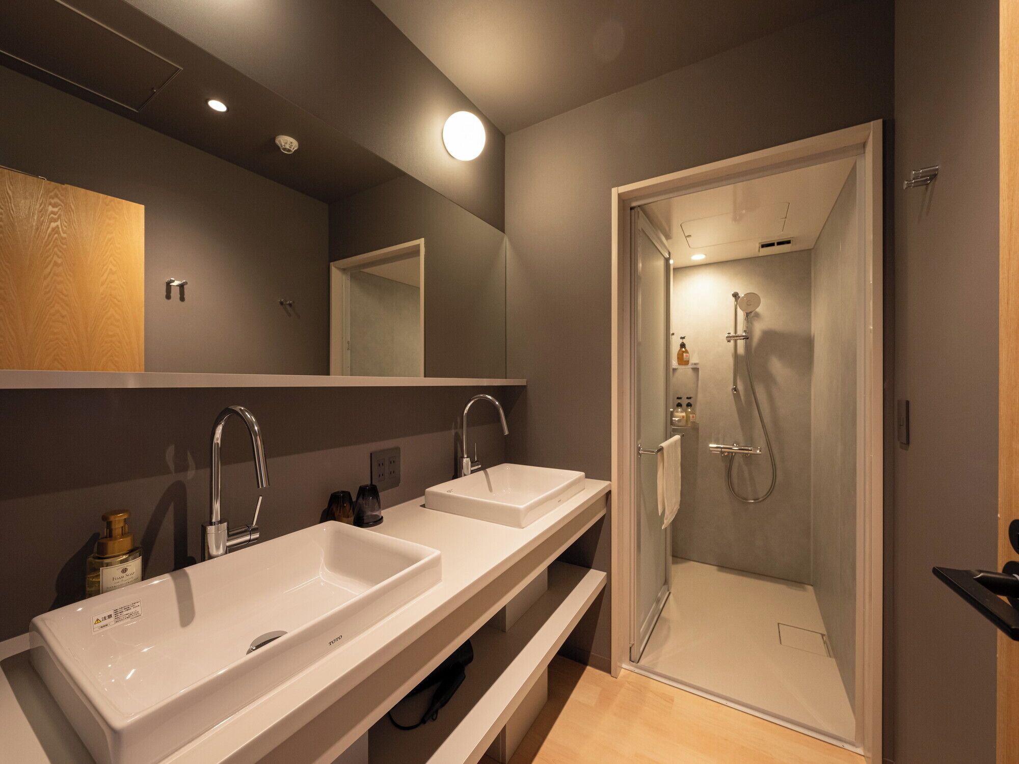 A modern bathroom with two sinks, a mirror, and a glass-enclosed shower.