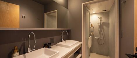 A modern bathroom with two sinks, a mirror, and a glass-enclosed shower.