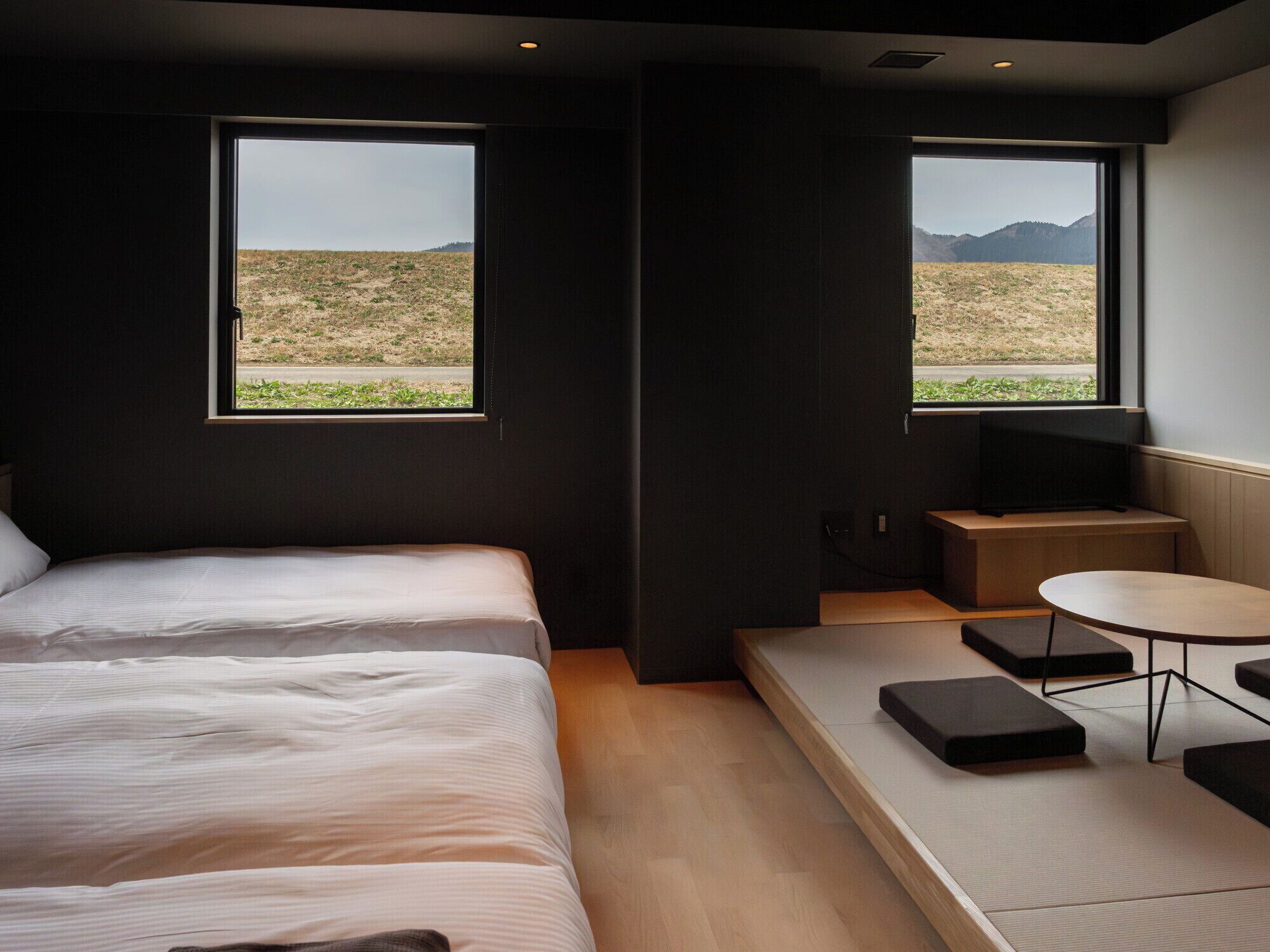 Een moderne kamer met twee bedden, een kleintje tafeltje en een televisie.