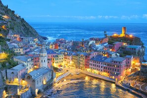 A coastal town with colorful buildings, a prominent tower, and a waterfront area.