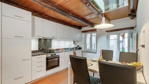 A modern kitchen with white cabinets, a marble countertop, and a dining area with black chairs and a table set for two. - Ca dal 1785 Centovalli With Balcony and Parking (Centovalli)