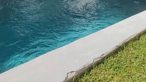 Ein Schwimmbecken mit Baum und Gartenmöbeln.
