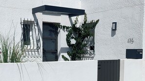 Ein modernes Haus mit weißer Fassade, einer schwarzen Tür und einem kleinen Fenster.