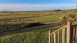A rural landscape with a wooden fence, a road, and distant houses. - Creag Mhor Lodge (Arisaig)