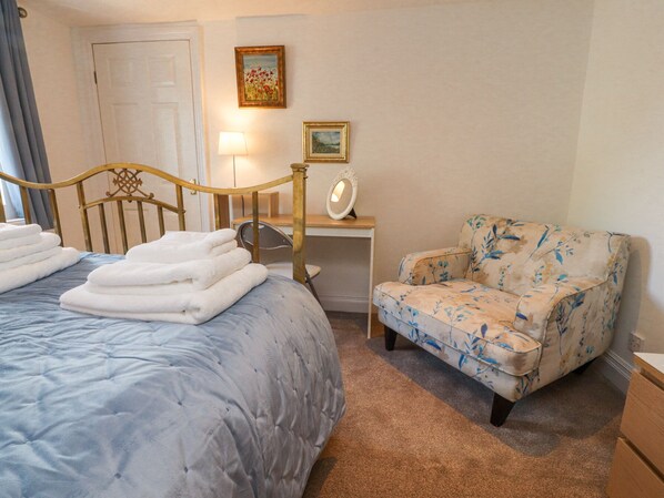 Une chambre à coucher avec un lit, une chaise, un bureau et une lampe.