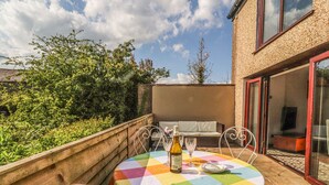 A small outdoor patio with a table set for two, a bottle of wine, and a sofa. - Stoneycross Cottage (Preston)
