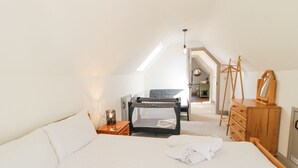 A bedroom with a bunk bed, a wooden dresser, a bedside table with a lamp, and a view of the bathroom. - Corradillar Quay Cottage (Enniskillen)